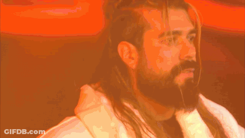A Man With Long Hair And A Beard Is Wearing A Robe GIF
