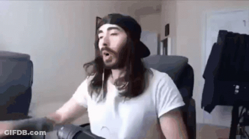 A Man With Long Hair And A Beard Is Wearing A White Shirt And A Black Hat . GIF