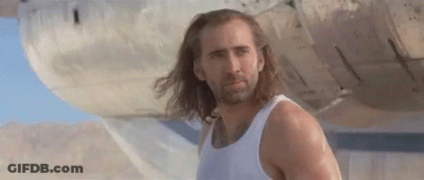 A Man With Long Hair And A Beard Is Wearing A White Tank Top . GIF