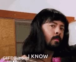 A Man With Long Hair And A Beard Is Wearing A Woman 'S Wig And Says `` I Know '' . GIF