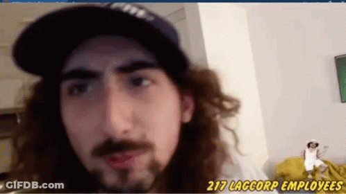 A Man With Long Hair And A Beard Is Wearing Red Lipstick And A Baseball Cap . GIF