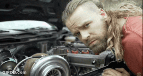 A Man With Long Hair And A Beard Is Working On A Car GIF