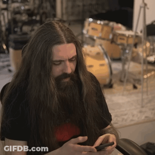 Man With Long Hair And Beard Looking At Phone GIF