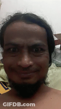A Man With Long Hair And A Beard Looks At The Camera With A Cardboard Box In The Background GIF