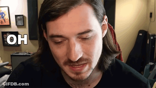 Man With Long Hair And Beard Looking At Camera With Oh Above Head GIF