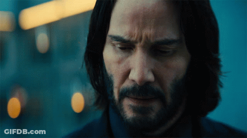 A Man With Long Hair And A Beard Looks Down At Something GIF