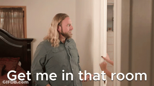A Man With Long Hair And A Beard Stands In Front Of A Door With The Words Get Me In That Room Below Him GIF