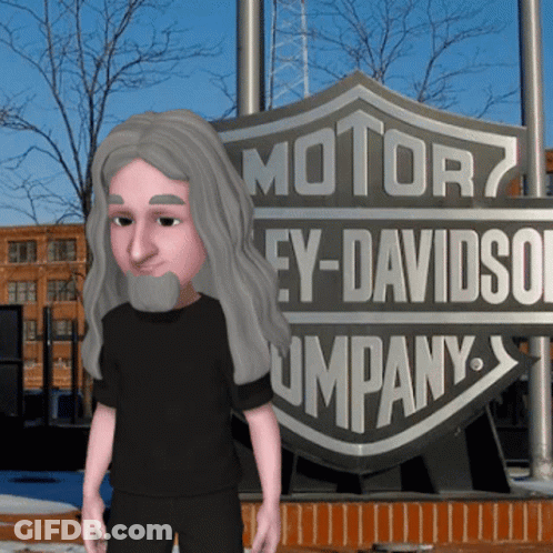 A Man With Long Hair And A Beard Stands In Front Of A Harley Davidson Company Sign GIF