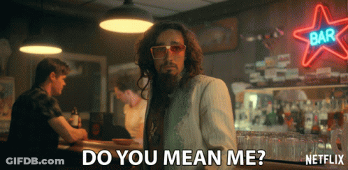 A Man With Long Hair And A Beard Stands In Front Of A Neon Sign That Says Bar GIF