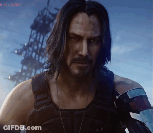 A Man With Long Hair And A Beard Stands In Front Of A Screen That Says R 21 22:03 GIF