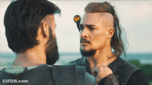 A Man With Long Hair And A Beard Stands Next To Another Man With Short Hair GIF