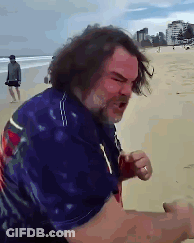 A Man With Long Hair And A Beard Stands On A Beach GIF
