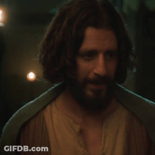 A Man With Long Hair And A Beard Wearing A Brown Shirt GIF
