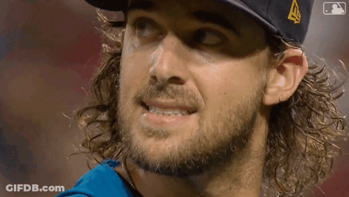 A Man With Long Hair And A Beard Wearing A Hat With A Mlb Logo On It GIF