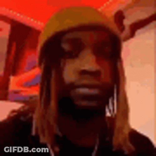 A Man With Long Hair And A Beard Wearing A Yellow Hat And Earrings . GIF