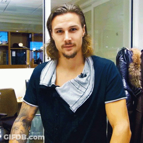 A Man With Long Hair And A Beard Wears A Black Shirt GIF