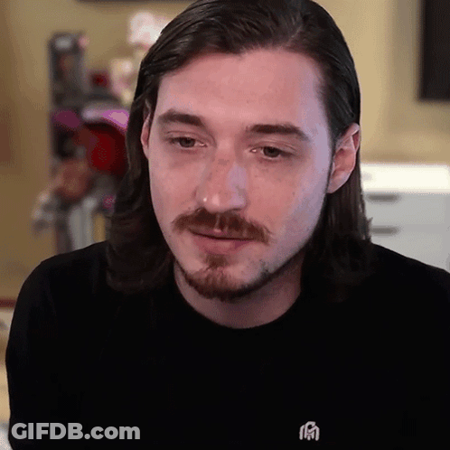 A Man With Long Hair And A Beard Wears A Black Shirt With A Chinese Symbol On The Front GIF