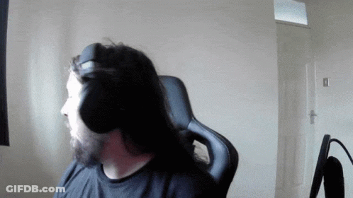 A Man With Long Hair And A Beard Wears Headphones While Sitting In A Chair GIF