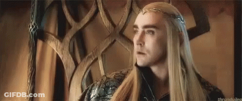 A Man With Long Hair And A Crown On His Head Is Sitting In A Chair . GIF