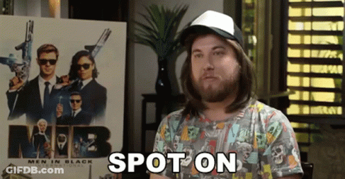 A Man With Long Hair And A Hat Is Standing In Front Of A Men In Black Poster . GIF