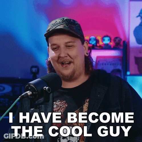 A Man With Long Hair And A Hat Says I Have Become The Cool Guy In Front Of A Microphone GIF
