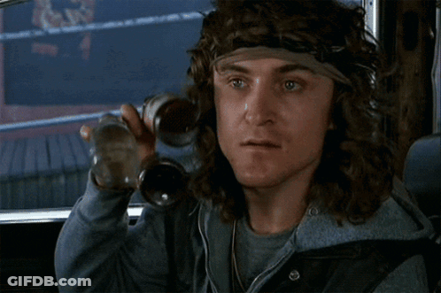 A Man With Long Hair And A Headband Is Holding A Bottle GIF