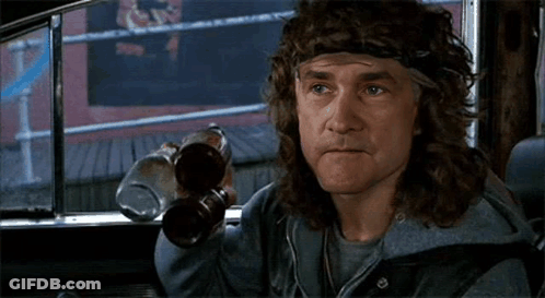 A Man With Long Hair And A Headband Is Sitting In A Car Holding Two Bottles Of Beer . GIF