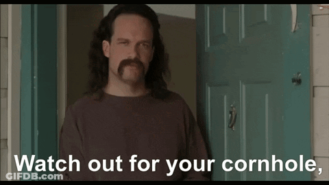 A Man With Long Hair And A Mustache Is Standing In Front Of A Door And Says " Watch Out For Your Cornhole " GIF