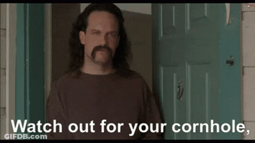 A Man With Long Hair And A Mustache Is Standing In Front Of A Door With The Words " Watch Out For Your Cornhole " Below GIF