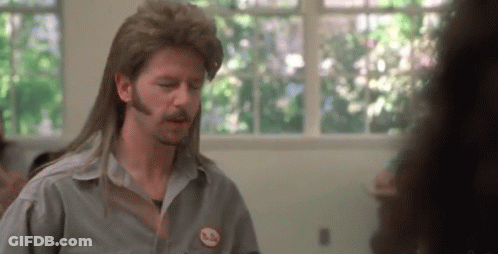 A Man With Long Hair And A Mustache Is Wearing A Mullet Wig And A Gray Shirt . GIF