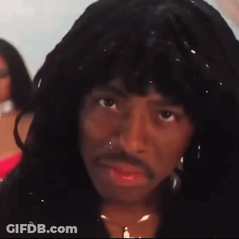 A Man With Long Hair And A Mustache Is Wearing A Wig And A Necklace . GIF