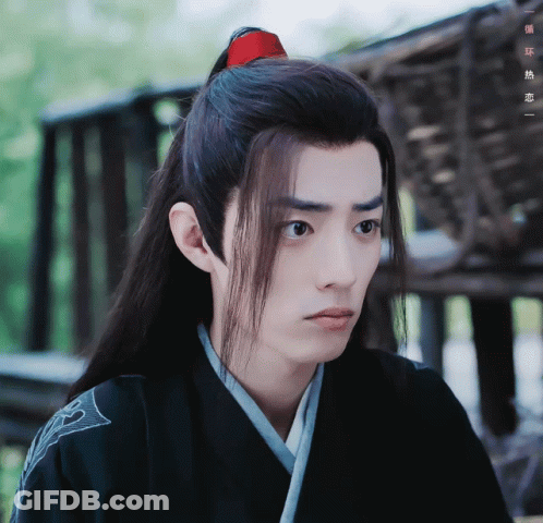 A Man With Long Hair And A Red Ponytail Looks To The Side GIF