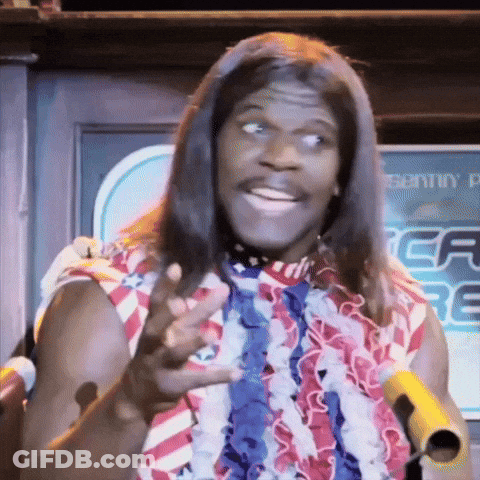 A Man With Long Hair And A Red White And Blue Shirt Is Holding A Microphone GIF