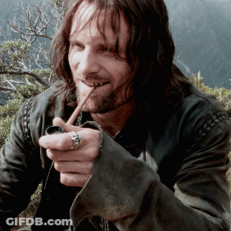 A Man With Long Hair And A Ring On His Finger Smoking A Pipe GIF