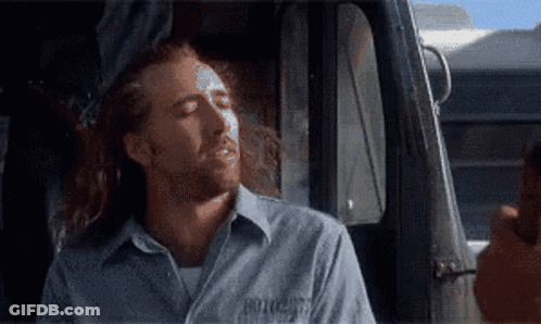 A Man With Long Hair And A Shirt That Says ' Prisoner ' On It Is Sitting In A Car GIF