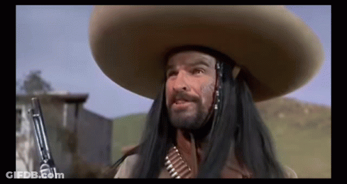 A Man With Long Hair And A Sombrero Is Holding A Gun In His Hand . GIF