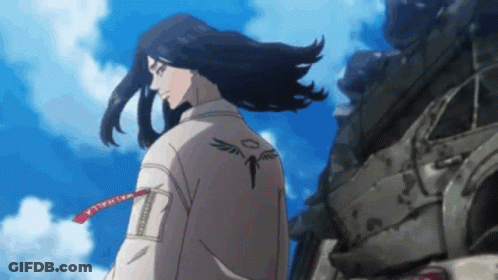 A Man With Long Hair And A Tattoo On His Back Is Standing In Front Of A Pile Of Junk . GIF