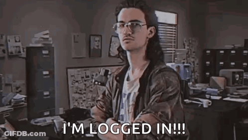 A Man With Long Hair And Glasses Is Sitting At A Desk In An Office . GIF