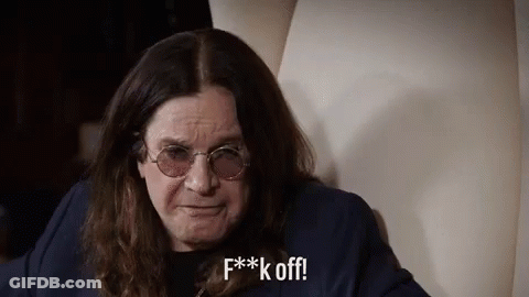 A Man With Long Hair And Glasses Is Sitting On A Chair And Making A Funny Face . GIF