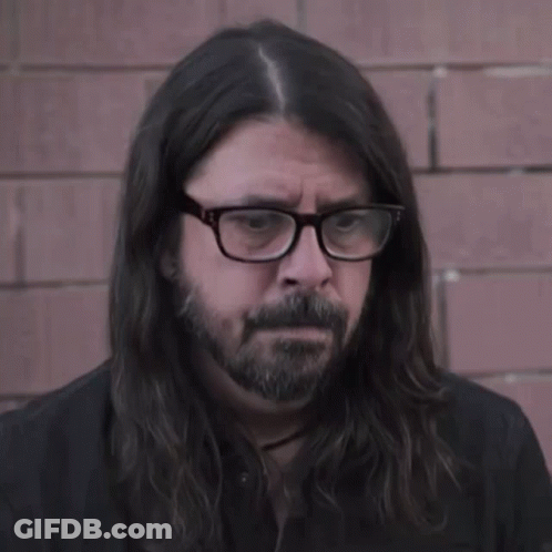 A Man With Long Hair And Glasses Looks Serious GIF