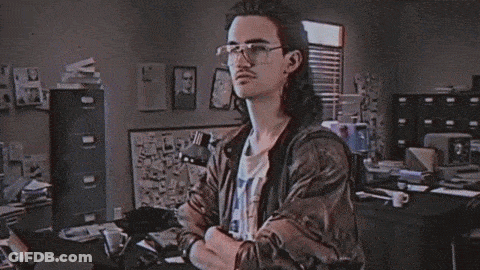 A Man With Long Hair And Glasses Stands In Front Of A Sign That Says Hackman GIF