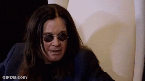 A Man With Long Hair And Sunglasses Is Sitting In A Chair . GIF