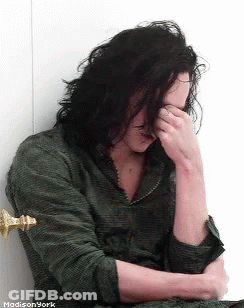 A Man With Long Hair Covering His Face With His Hand GIF