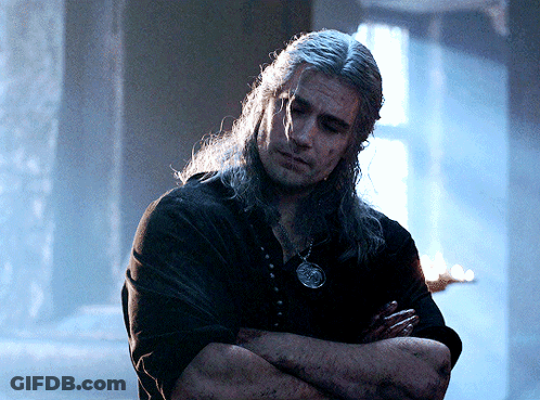 A Man With Long Hair Has His Arms Crossed And Is Wearing A Necklace GIF