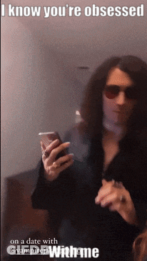 A Man With Long Hair Is Holding A Cell Phone With A Caption That Says I Know You 'Re Obsessed GIF