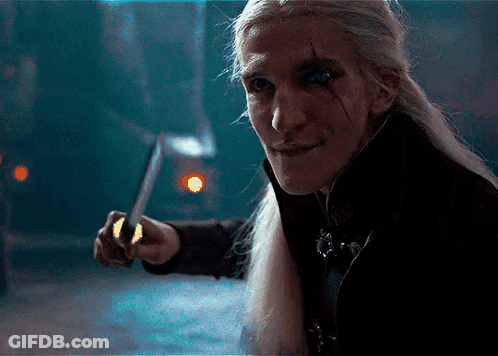 A Man With Long Hair Is Holding A Knife In His Hand GIF