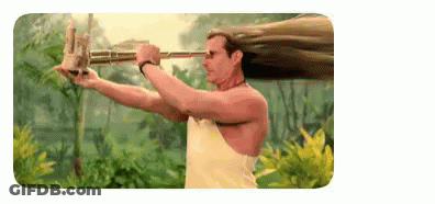 A Man With Long Hair Is Holding A Long Stick In His Hand . GIF