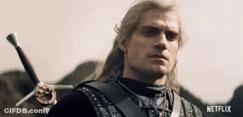 A Man With Long Hair Is Holding A Sword In His Right Hand And Looking At The Camera . GIF
