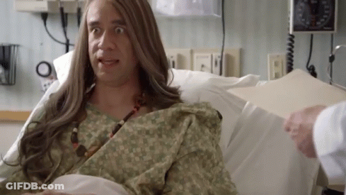 A Man With Long Hair Is Laying In A Hospital Bed With A Doctor . GIF