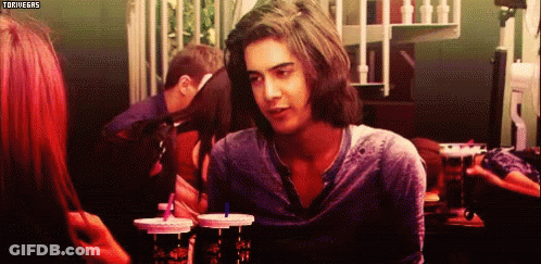 A Man With Long Hair Is Looking At A Woman While Sitting At A Table With Drinks In Front Of Him .. GIF